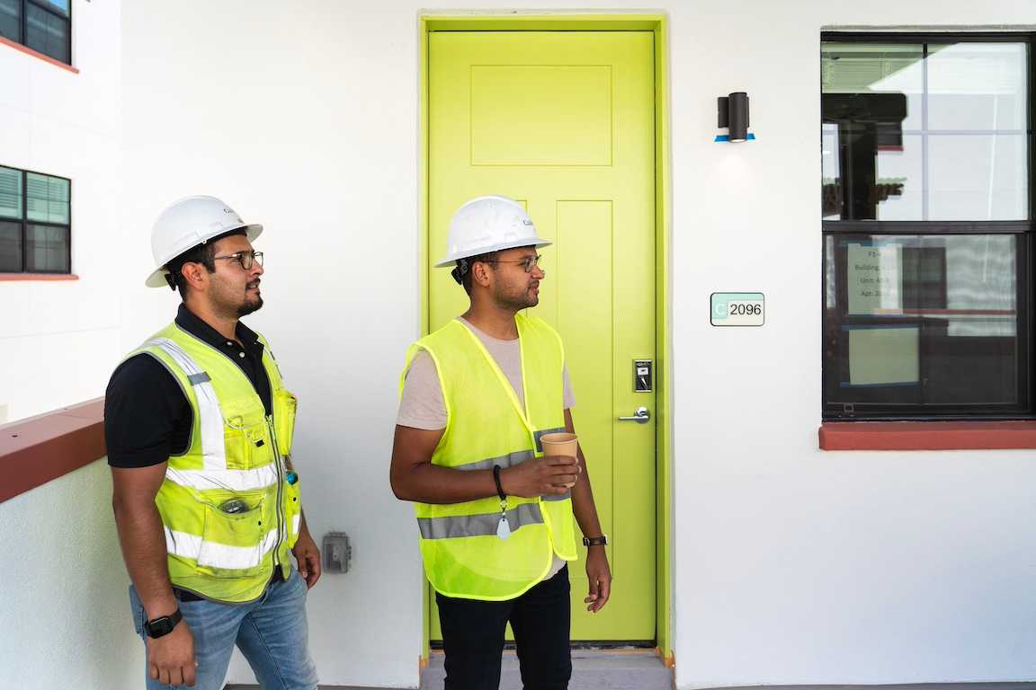 On-site in front of a colorful apartment door and wearing construction gear